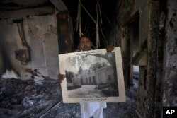 A government employee displays an old picture to media members inside the Radio Pakistan building burnt in the Wednesday's clashes between police and the supporters of Pakistan's former Prime Minister Imran Khan, in Peshawar, Pakistan, May 11, 2023.