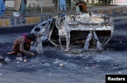 A ragpicker collects usable items next to the debris of a burnt vehicle following a protest by the supporters of Pakistan's former Prime Minister Imran Khan against his arrest, in Peshawar, Pakistan, May 11, 2023. REUTERS/Fayaz Aziz