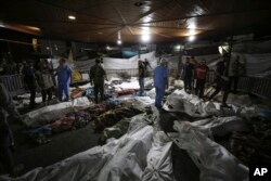 Bodies of Palestinians killed by an explosion at the Ahli Arab hospital are gathered in the front yard of the al-Shifa hospital, in Gaza City, central Gaza Strip, Oct. 17, 2023.