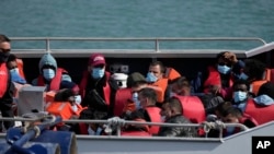 FILE - People thought to be migrants who undertook the crossing from France in small boats and were picked up in the Channel, wait to be disembarked from a British border force vessel, in Dover, south east England, on June 17, 2022.