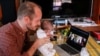 FILE - Namibian citizen Phillip Luhl holds one of his twin daughters as he speaks to his Mexican husband Guillermo Delgado via Zoom meeting in Johannesburg, South Africa, April 13, 2021.