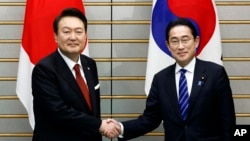Presiden Korea Selatan Yoon Suk Yeol, kiri, dan Perdana Menteri Jepang Fumio Kishida, berjabat tangan, menjelang pertemuan bilateral mereka di Kantor PM Jepang di Tokyo, Kamis, 16 Maret 2023. 