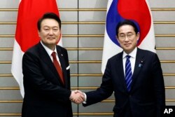 Presiden Korea Selatan Yoon Suk Yeol (kiri,) berjabat tangan dengan Perdana Menteri Jepang Fumio Kishida, menjelang pertemuan bilateral di Kantor Perdana Menteri Jepang di Tokyo, Kamis, 16 Maret 2023. (Kiyoshi Ota/Pool Photo melalui AP)