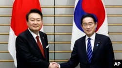 Presiden Korea Selatan Yoon Suk Yeol (kiri) berjabat tangan dengan dan Perdana Menteri Jepang Fumio Kishida, menjelang pertemuan bilateral mereka di Kantor Perdana Menteri Jepang, di Tokyo, Kamis, 16 Maret 2023. (Kiyoshi Ota/Pool Photo via AP)