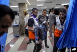 A wounded Palestinian girl is carried into the emergency room of the al-Shifa hospital, following Israeli airstrikes on Gaza City, central Gaza Strip, Oct. 17, 2023.