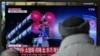 Men watch a television showing a news broadcast with file footage of a North Korean military parade, at a railway station in Seoul, Feb. 20, 2023. 