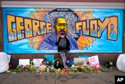 FILE - Damarra Atkins pays respect to George Floyd at a mural at George Floyd Square in Minneapolis, Minnesota, April 23, 2021.