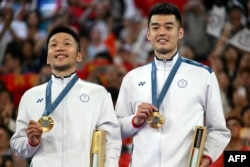 Peraih medali emas Taiwan Lee Yang dan Wang Chi-lin memamerkan medali mereka di podium pada upacara penyerahan medali bulu tangkis ganda putra selama Olimpiade Paris 2024 di Porte de la Chapelle Arena di Paris, 4 Agustus 2024. (Arun SANKAR / AFP)