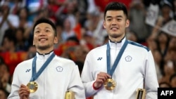 Taiwan's gold medallists Lee Yang and Wang Chi-lin celebrate with their medals on the podium at the men's doubles badminton medal ceremony during the Paris 2024 Olympic Games at Porte de la Chapelle Arena in Paris, Aug. 4, 2024.