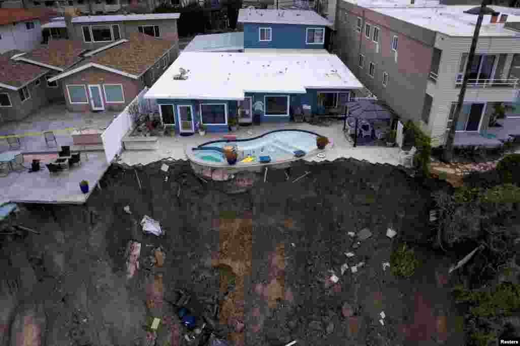 A backyard pool is left hanging on a cliffside after torrential rain brought havoc on the beachfront town of San Clemente, California, March 16, 2023. 