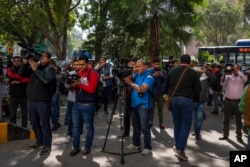 Media personnel report while standing outside a building housing BBC office in New Delhi, India, Feb. 14, 2023.