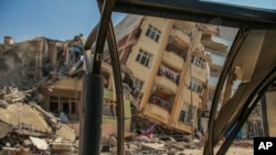 Uništena zgrada naslonjena na susjednu kuću nakon potresa u Samandagu, južna Turska, srijeda, 22. veljače 2023. 