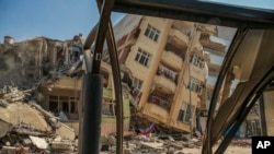 A destroyed building leans on a neighboring house following the earthquake in Samandag, southern Turkey, Feb. 22, 2023. 