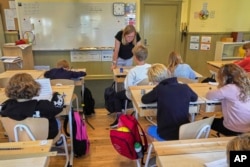 FILE - A teacher helps students practice their handwriting at the Djurgardsskolan elementary school in Stockholm, Sweden, Aug. 31, 2023. (AP Photo/David Keyton)