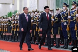 In this photo released by Xinhua News Agency, Chinese Premier Li Qiang, left, and Malaysia's Prime Minister Anwar Ibrahim review an honor guard during a welcome ceremony at the Great Hall of the People in Beijing, Saturday, April 1, 2023.