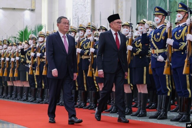 In this photo released by Xinhua News Agency, Chinese Premier Li Qiang, left, and Malaysia's Prime Minister Anwar Ibrahim review an honor guard during a welcome ceremony at the Great Hall of the People in Beijing, Saturday, April 1, 2023.