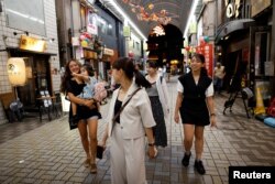 Rickshaw puller Shiori Yoshida, 28, and her daughter Yui, 3, walk to a restaurant for drinks with fellow pullers after work, at the Asakusa district in Tokyo, Aug. 17, 2023.