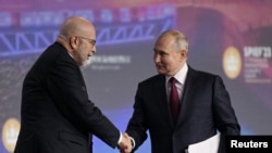 FILE - Russian President Vladimir Putin shakes hands with moderator Dimitri Simes during a session of the St. Petersburg International Economic Forum in St. Petersburg, Russia, June 16, 2023. Simes' Virginia home was the target of a recent FBI raid.