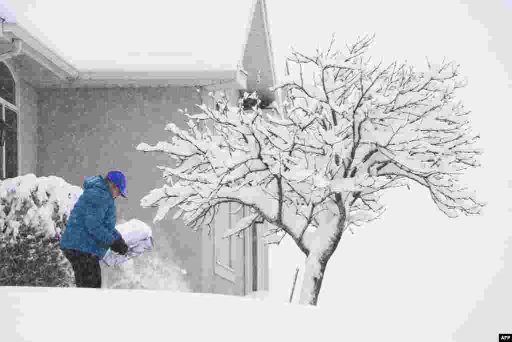A person shovels their sidewalk in Provo, Utah, Feb. 22, 2023.&nbsp;Powerful winter storms lashed the United States, with heavy snow snarling travel across wide areas, even as unusual warmth was expected in others.