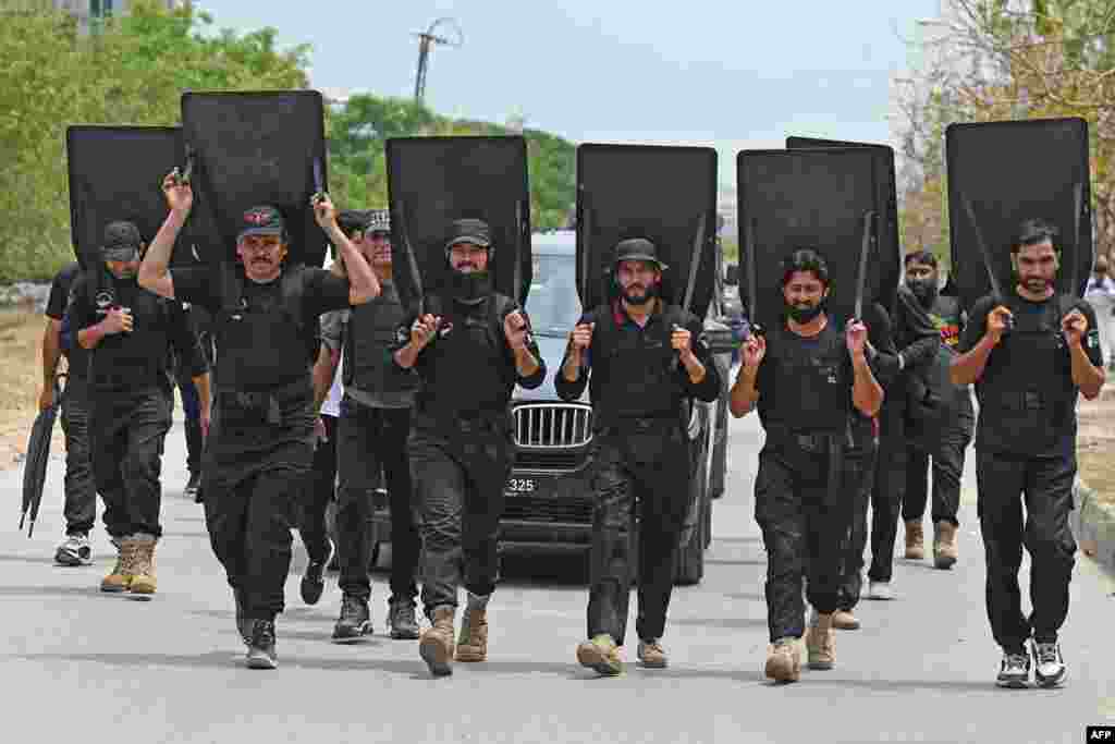 Security personnel with ballistic shields escort a vehicle carrying Pakistan's former prime minister Imran Khan as he leaves after appearing before an anti-terrorism court in Islamabad.