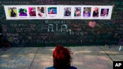 FILE - A person visits a makeshift memorial near the scene of a shooting at a supermarket, in Buffalo, May 19, 2022. The city of Buffalo paused Sunday to mark the passing of one year since the attack.