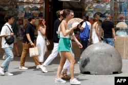 A woman fans herself to cool off during a heat wave in Madrid on Aug. 9, 2023. (Photo by JAVIER SORIANO / AFP)