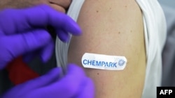 In this file photo, a doctor fixes a patch on the arm of an employee after a vaccination with the Pfizer BioNTech vaccine at the vaccination center of CHEMPARK operator CURRENTA in Leverkusen, western Germany, on June 22, 2021 (Photo by Ina FASSBENDER / AFP)