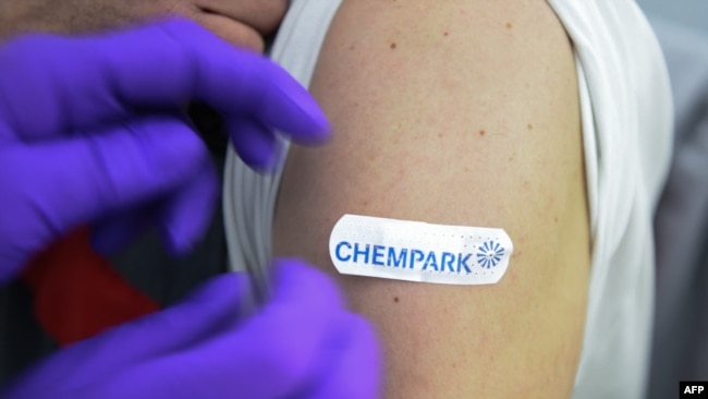 In this file photo, a doctor fixes a patch on the arm of an employee after a vaccination with the Pfizer BioNTech vaccine at the vaccination center of CHEMPARK operator CURRENTA in Leverkusen, western Germany, on June 22, 2021 (Photo by Ina FASSBENDER / AFP)