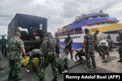 TNI memuat barang ke dalam kapal saat mereka menuju ke pulau dekat gunung berapi Gunung Ruang di pelabuhan Manado, Sulawesi Utara, pada 18 April 2024. (Foto: Ronny Adolof BUOL/AFP)
