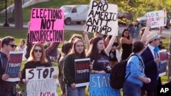 People protest outside a building on the campus of Saint Anselm College hosting a CNN televised town hall gathering with former President Donald Trump, May 10, 2023, in Manchester, NH.