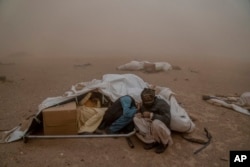 Afghan people affected by the earthquake try to shelter in their tent during a powerful sandstorm, after an earthquake in Zenda Jan district in Herat province, western of Afghanistan, Oct. 12, 2023.