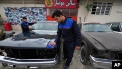 FILE - Workers clean an under restored Cadillac Seville at Khosro Dahaghin's workshop in Roudehen, some 30 miles (45 kilometers) east of downtown Tehran, Iran, June 7, 2023.