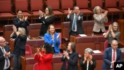 Senator bertepuk tangan setelah disahkannya suara di ruang Senat, Gedung Parlemen Australia, di Canberra, Senin, 19 Juni 2023. Senat memilih untuk mengadakan referendum tahun ini terkait pengakuan suara penduduk asli dalam konstitusi. (Mick Tsikas/AAP via AP)