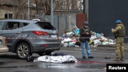 Police investigators work next to the body of a person killed by a Russian strike, in a supermarket parking lot, in Kherson, Ukraine, March 11, 2023.