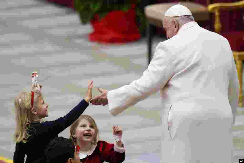 Папата Фрањо се поздравува со деца додека го слави својот роденден за време на мисата во салата Павле VI, во Ватикан.
