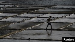 বাংলাদেশের কক্সবাজারে একটি লবণের ক্ষেতের মধ্য দিয়ে হেঁটে যাচ্ছে একজন শ্রমিক। ২১ মার্চ, ২০১৮। (ফাইল ছবি) 