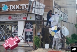 Residents clean up the entrance of a drugstore damaged by Hurricane Beryl in Tulum, Mexico, July 5, 2024.