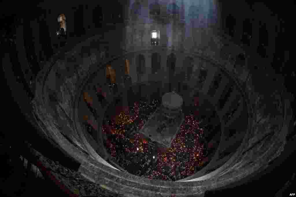 Orthodox Christians gather with lit candles around the Edicule, traditionally believed to be the burial site of Jesus Christ, during the annual Holy Fire ceremony in Jerusalem's Holy Sepulchre church, a day before Orthodox Easter, May 4, 2024. 