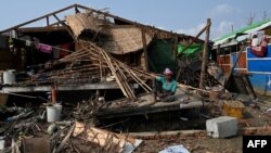 A Rohingya woman sits by her destroyed house at Ohn Taw Chay refugee camp in Sittwe on May 16, 2023, in the aftermath of Cyclone Mocha's landfall. 