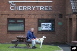 A voter waits with his dog after casting his vote at the Cherry Tree public house that was used a polling station in Urpeth, County Durham, northern England, July 4, 2024.