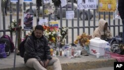 A Venezuelan migrant sits on the sidewalk where an altar was created with candles and photos outside the Mexican immigration detention center that was the site of a deadly fire, in Ciudad Juarez, Mexico, March 30, 2023. 