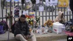 Seorang migran Venezuela duduk di trotoar tempat altar dengan lilin dan foto di luar pusat penahanan imigrasi Meksiko yang terbakar,di Ciudad Juarez, Meksiko, Kamis, 30 Maret 2023. (AP/Fernando Llano)