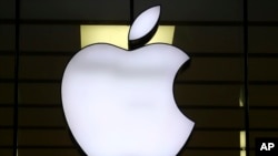 FILE - The Apple logo is illuminated at a store in the city center of Munich, Germany, Dec. 16, 2020. European Union fines Apple nearly $2 billion for unfairly favoring its own music streaming service over rivals. 