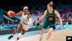 Ezinne Kalu, of Nigeria, drives on Sami Whitcomb, of Australia, in a women's basketball game at the 2024 Summer Olympics, in Villeneuve-d'Ascq, France, July 29, 2024.