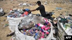 FILE - This file photo taken on June 5, 2020 shows a garbage collector gathering recyclable plastic at the Ban Tarn landfill site in the northern Thai province of Chiang Mai. 