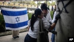 Miembros de la comunidad israelí en Colombia borran graffiti anntisemita en la pared de la embajada de Israel en Bogotá el 9 de octubre de 2023.