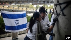 Members of Colombia's Israeli community erase antisemitic graffiti outside Israel's Embassy in Bogota, Colombia, Oct. 9, 2023, two days after Hamas fighters launched a deadly surprise attack against Israel.