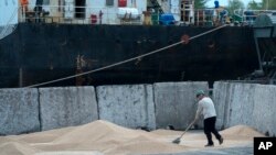 FILE - Workers load grain at a grain port in Izmail, Ukraine, April 26, 2023. 