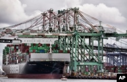 FILE - A sailboat passes a cargo ship unloading containers the port of Los Angeles in San Pedro, June 15, 2023. The U.S. ran a trade deficit of about $383 billion with China in 2022.