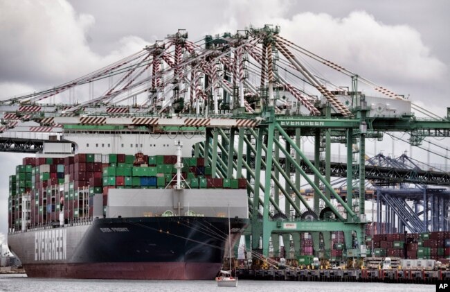 FILE - A sailboat passes a cargo ship unloading containers the port of Los Angeles in San Pedro, June 15, 2023. The U.S. ran a trade deficit of about $383 billion with China in 2022.